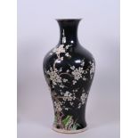 A Chinese famille noir porcelain vase decorated with birds perched on a prunus tree, six character