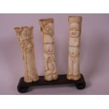 A set of three C19th Chinese carved bone figures of sages, 6" high, on a hardwood stand