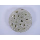 A Chinese celadon jade pendant with carved and pierced scrolling decoration, 2" diameter