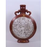 A Chinese twin handled pottery moon flask with a copper lustre glaze and decorative raised panel