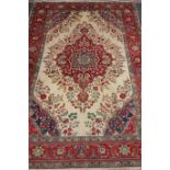 Persian Tabriz carpet, central floral medallion over cream ground spandrels red floral borders,