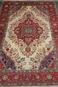 Persian Tabriz carpet, central floral medallion over cream ground spandrels red floral borders,