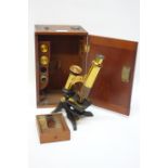 Small early 20th century part brass monocular microscope with additional lens and slides in fitted