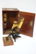 Small early 20th century part brass monocular microscope with additional lens and slides in fitted