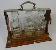 Edwardian three bottle Tantalus with cut glass decanters. Retailed by Rowe Jewellery, Marlow.