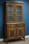 Late 19th century heavily carved oak dresser with raised bookcase enclosed by two glazed doors,
