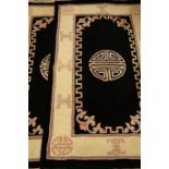Pair of black ground Chinese washed woollen shou motif rugs 154cm x 92cm (2)