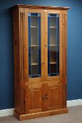 Pine bookcase enclosed by two blue tinted lead glazed doors, with double cupboard below, W101cm,
