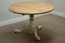 Circular light oak tilt top table, on turned painted pedestal with three splayed legs, D109cm,