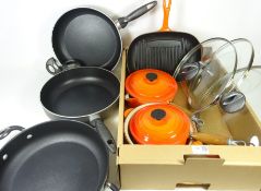 Two orange lidded Le Creuset sauce pans,