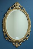 Ornate gilt cast metal oval mirror with bevelled glass,