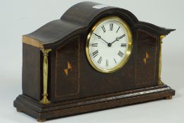 Early 20th century inlaid oak arched top mantle clock with brass columns and circular dial on brass