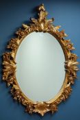 Ornate floral gilt framed mirror with oval bevelled glass,