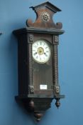 Late 19th century musical wall clock, stained architectural case with circular dial,