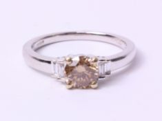 White gold diamond ring set with a single round champagne stone and baguette diamond shoulders