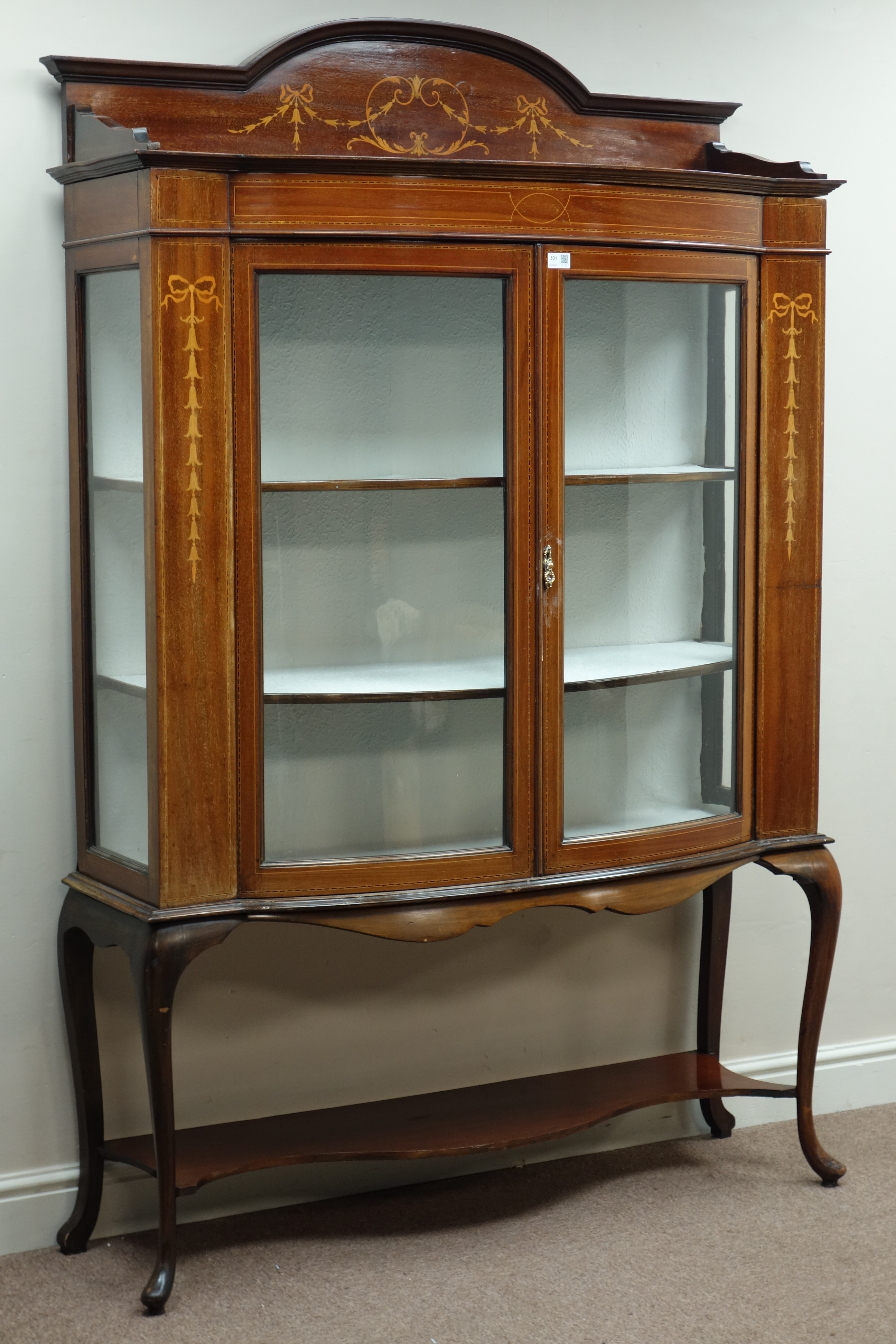 Edwardian inlaid mahogany bow front display cabinet, enclosed by two curved glazed doors,