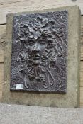 Pressed metal green man water feature mounted on rectangular stone block,