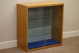 Light oak illuminated display cabinet enclosed by two sliding glass doors, adjustable glass shelves,