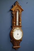 Early 20th century aneroid barometer and thermometer in carved oak case,
