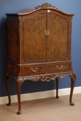 20th century figured walnut drinks cabinet, shaped top over two doors,