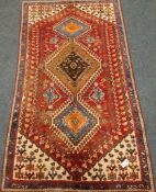 Persian Shiraz red ground rug, triple pole medallion, stylised motifs,