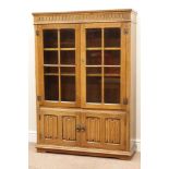 Light oak bookcase enclosed by two glazed doors with linenfold detail, W97cm,