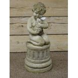 Composite stone putto holding rabbit, on circular fluted plinth,