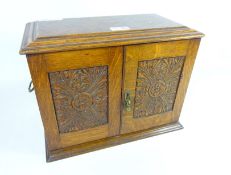 Edwardian oak smoker's cabinet with carved panels and later contents including a brass tobacco jar
