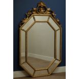 Octagonal wall mirror in gilt frame with sectional bevelled mirrored border and ornate pediment,