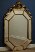 Octagonal wall mirror in gilt frame with sectional bevelled mirrored border and ornate pediment,