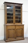 Edwardian oak bookcase on cupboard, raised bookcase enclosed by two glazed doors, four shelves,