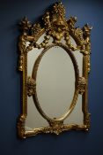 Ornate gilt framed wall mirror decorated with floral baskets and cherubs, oval centre,