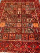 Persian Bakhtiari garden rug carpet, red ground, with stylised floral motifs,