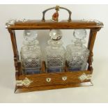 Early 20th Century oak Tantalus with silver plated mounts and three cut glass decanters,