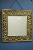 Early 20th century embossed brass mirror with bevelled glass,
