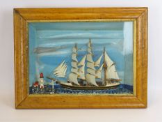 Cased niave diorama of a three master under full sail, passing a lighthouse, in maple frame, W41cm,