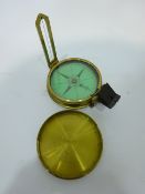 Late 19th century brass pocket compass and cover, green paper dial inscribed 'Elliott Bros Strand,