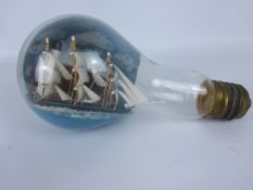 Small diorama of a three masted clipper passing a Lighthouse in a large glass light bulb,