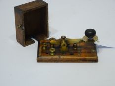 20th century Morse code key, brass with ebonised handle on rectangular mahogany base with cover,