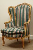 French style carved walnut wingback armchair upholstered in striped fabric with loose seat cushion