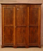 Edwardian figured mahogany serpentine triple wardrobe, three panelled and banded doors,