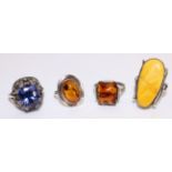 Three amber set silver rings and a ring set with a blue stone and marcasite in a metal box