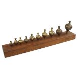 A collection of 10 fairly graduated steel tipped brass plumb bobs on mahogany display board G+