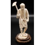 A Japanese sectional ivory carving, a standing farmer carrying a hoe, at his feet a small pumpkin,