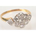 A nine stone flowerhead diamond cluster ring with diamond set shoulders.