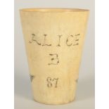 A horn scrimshaw style beaker decorated with a sailing ship and inscribed Alice B 87, height 7.5cm.