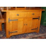 An light oak side cabinet in Arts and Crafts style fitted two doors over a pair of panelled doors,
