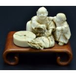 A Japanese ivory okimono, a seated father mixing a paste in a small bowl,
