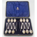 A set of twelve silver ornate coffee spoons and sugar tongs, Sheffield 1897, makers mark GH, cased.