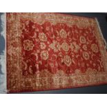 A machine made rug, Ziegler style, the madder field with a central medallion, scrolling vines,